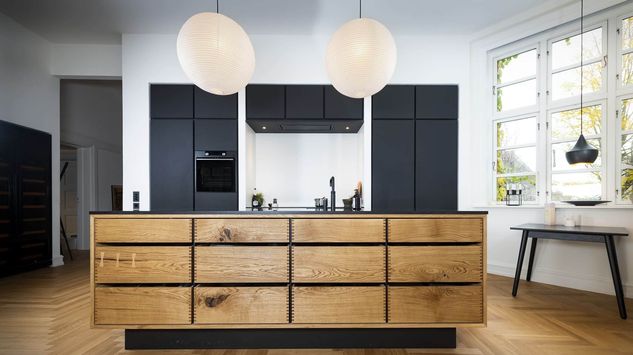 Minimalistisk køkken med træskuffer og sorte skabe fra Scharlingwood