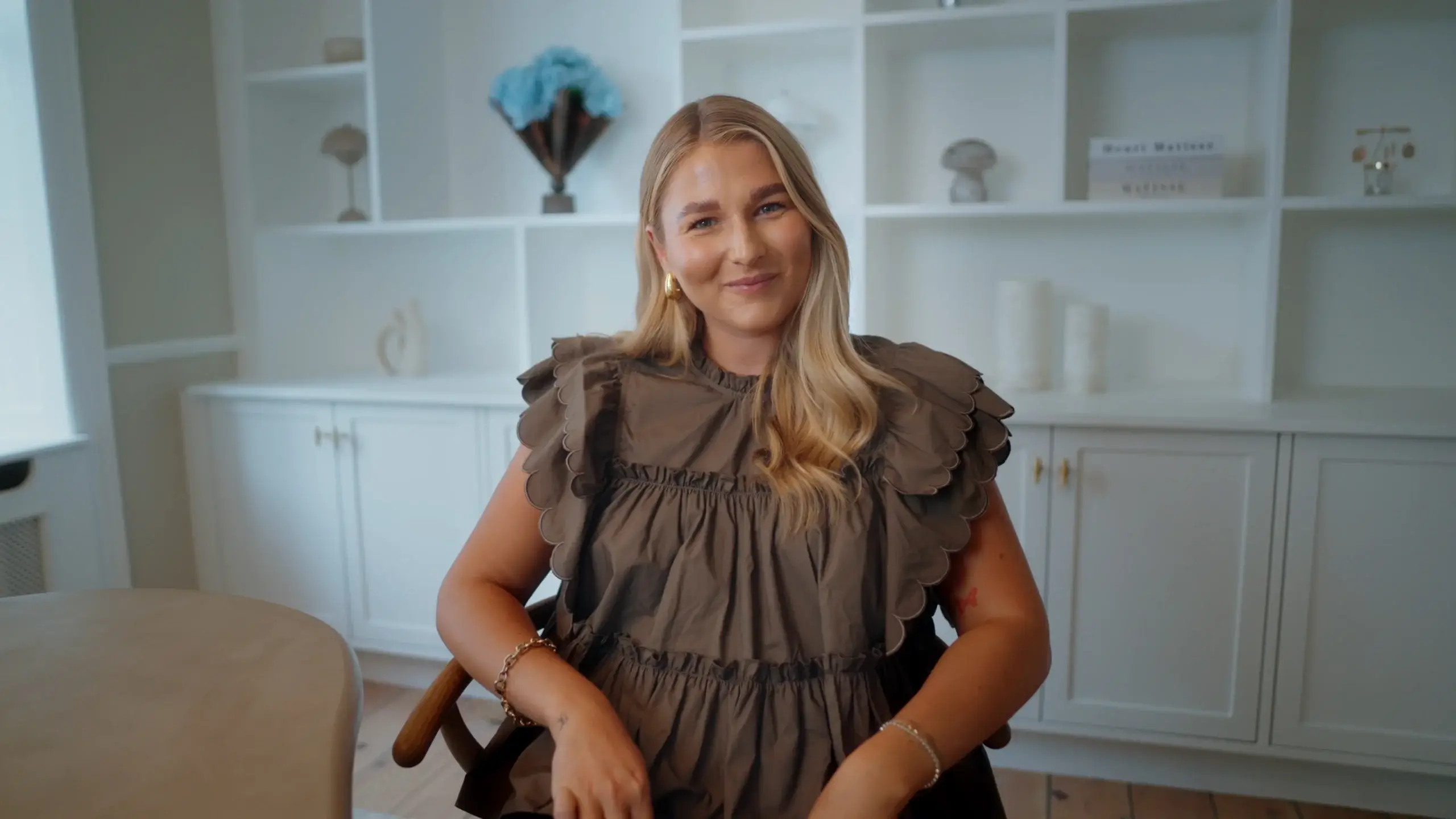 Founder fra Aurora sidder smilende i et lyst kontormiljø under optagelse af en “Om os”-video produceret af Unlimited Squares.