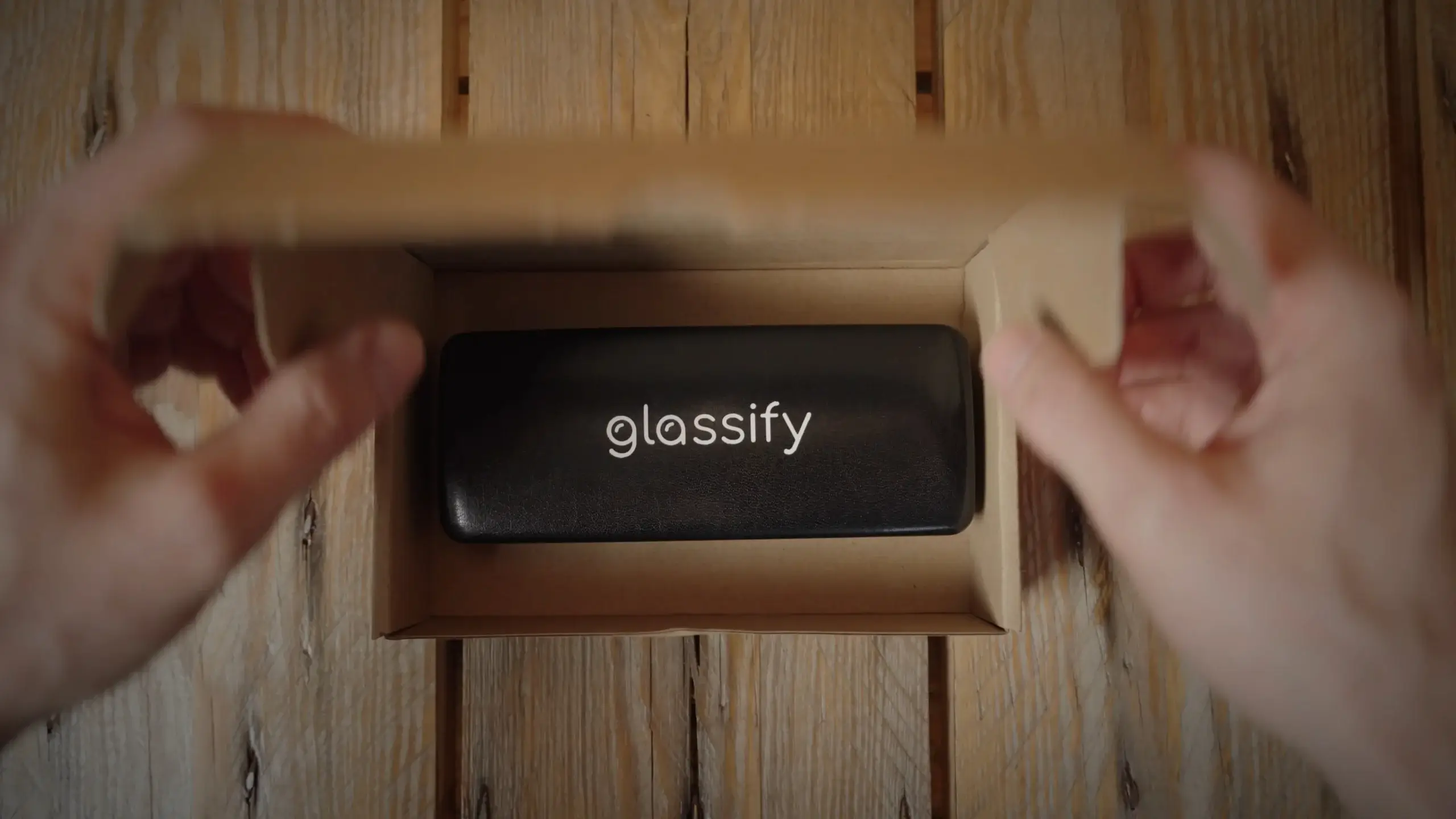 Kunde pakker brilleetui ned i papkasse for at sende til Glassify til udskiftning af glas.